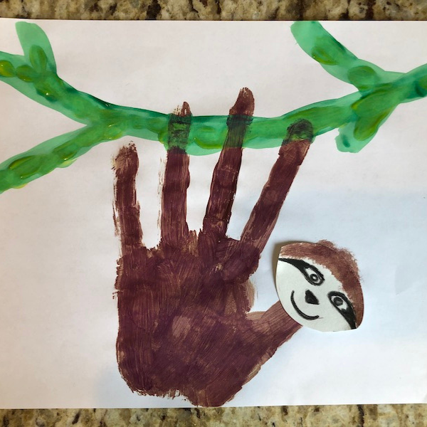 sloth2 A brown painted handprint sloth on a green branch.