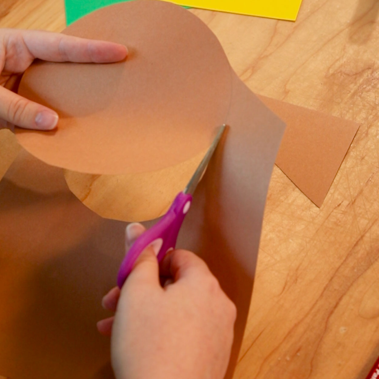 Brown circle being cut from construction paper