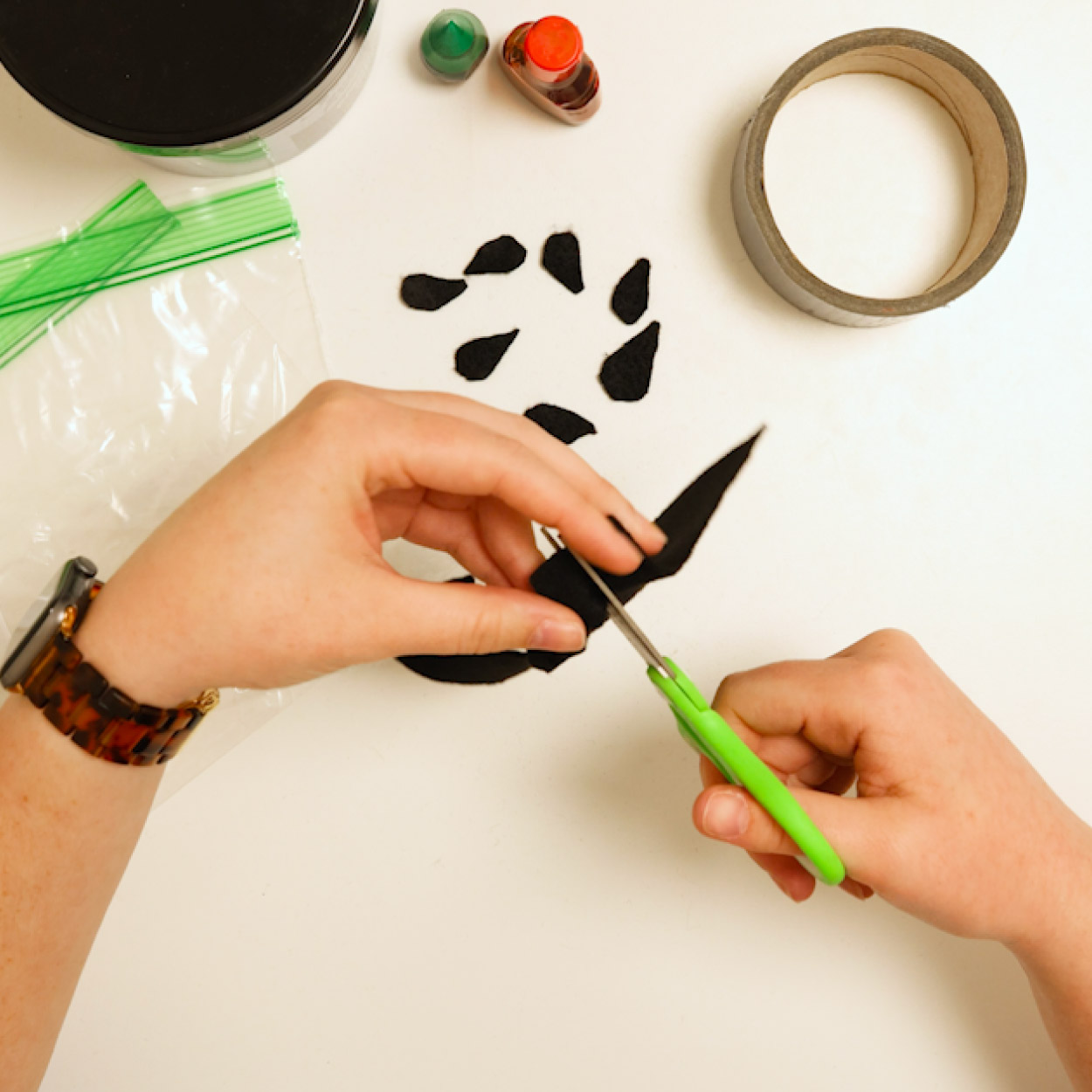 Cut small teardrop seed shapes from a sheet of black foam with scissors
